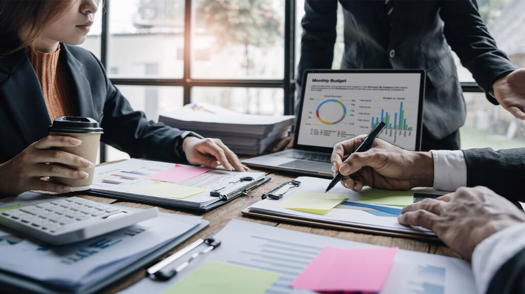 Business professionals analyzing monthly budget reports and financial data with charts and graphs during team meeting