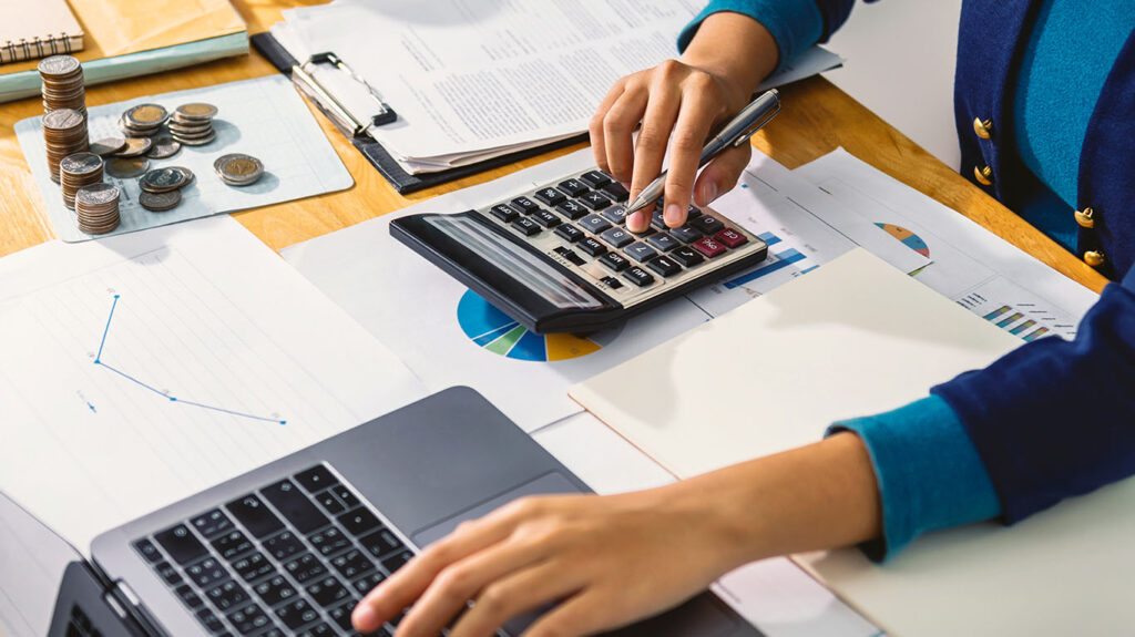 Personal finance management with calculator, coins, and financial reports on wooden desk