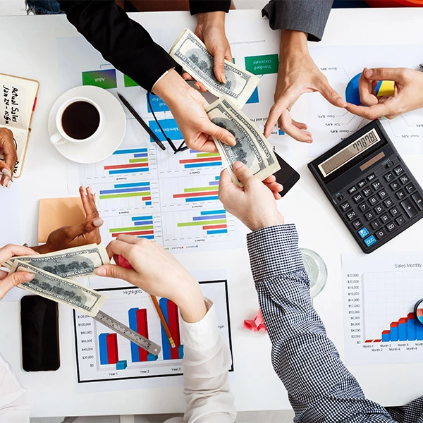 "Business team analyzing financial data with cash flow charts, calculator and dollar bills on white desk"