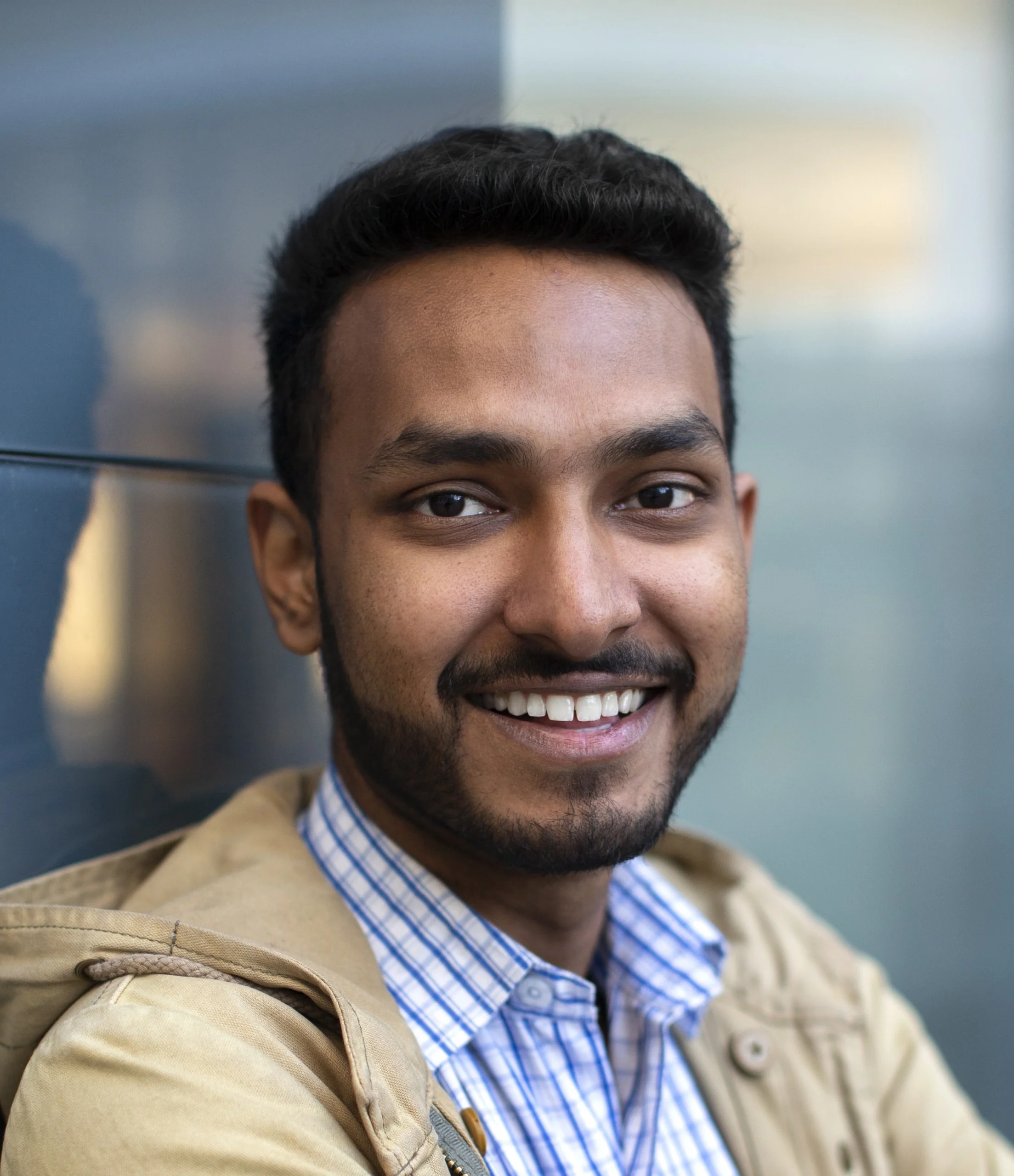 smiling-young-indian-professional-wearing-checkered-shirt-and-beige-jacket